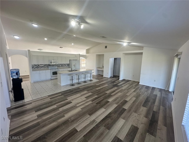 unfurnished living room featuring hardwood / wood-style flooring and vaulted ceiling