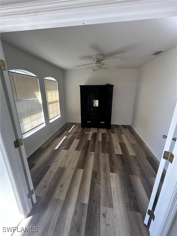 empty room featuring dark wood-type flooring and ceiling fan