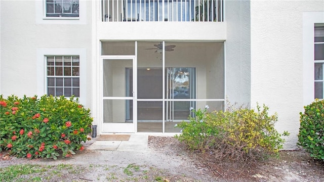 view of exterior entry with a balcony and ceiling fan