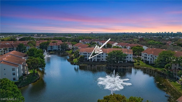 aerial view at dusk featuring a water view