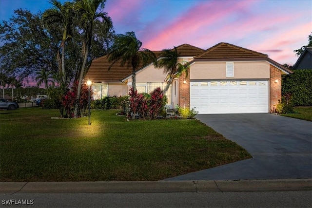 view of front of property with a garage, a lawn, driveway, and stucco siding