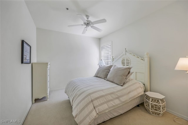 bedroom featuring light colored carpet, baseboards, and a ceiling fan