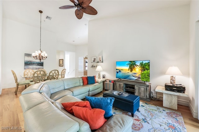 living room featuring ceiling fan with notable chandelier, high vaulted ceiling, and light wood-type flooring