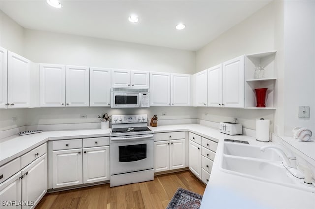 kitchen featuring white cabinetry, sink, white appliances, and light hardwood / wood-style flooring