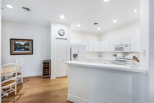 kitchen with wine cooler, white cabinets, kitchen peninsula, white appliances, and light hardwood / wood-style flooring