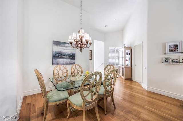 dining space featuring an inviting chandelier, hardwood / wood-style floors, and a high ceiling