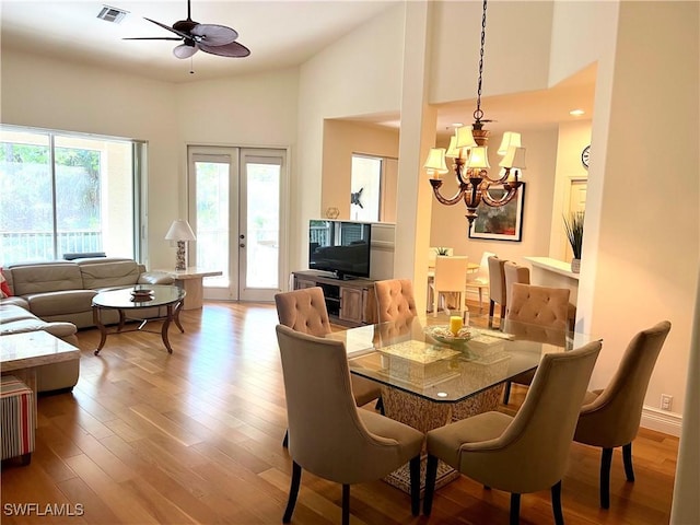 dining area featuring high vaulted ceiling, visible vents, ceiling fan with notable chandelier, and wood finished floors