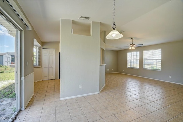 unfurnished room with ceiling fan, a wealth of natural light, and light tile patterned floors