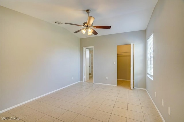 unfurnished bedroom featuring lofted ceiling, light tile patterned floors, ceiling fan, a walk in closet, and a closet