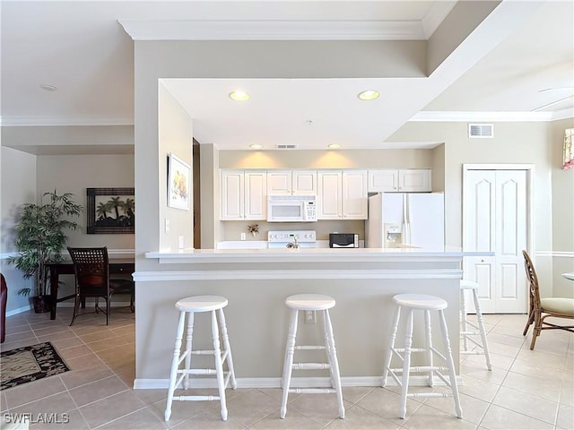 kitchen featuring a kitchen breakfast bar, ornamental molding, white cabinets, and white appliances