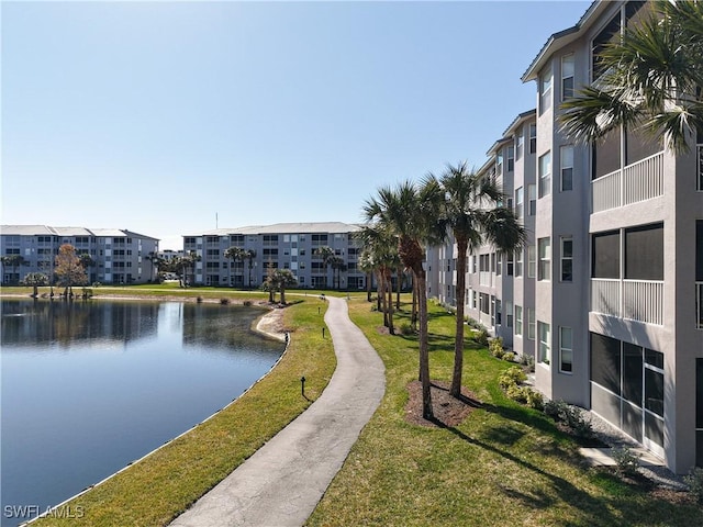 surrounding community with a water view and a lawn