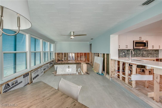 interior space featuring ceiling fan, a sink, and visible vents