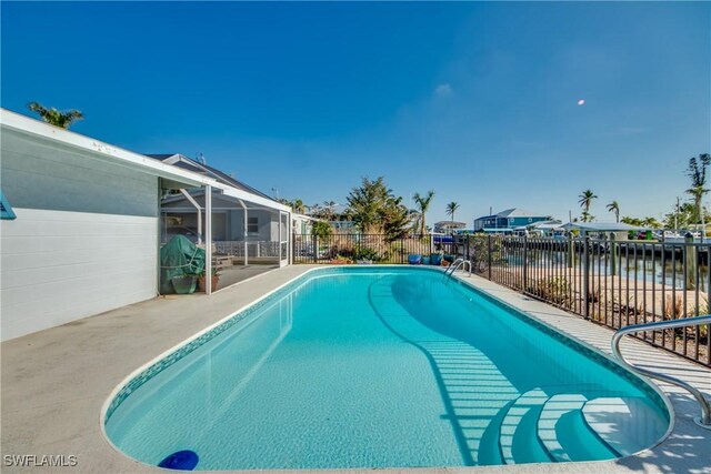 view of pool featuring a water view, a patio, and glass enclosure