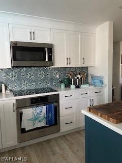 kitchen featuring appliances with stainless steel finishes, white cabinets, light wood finished floors, and tasteful backsplash