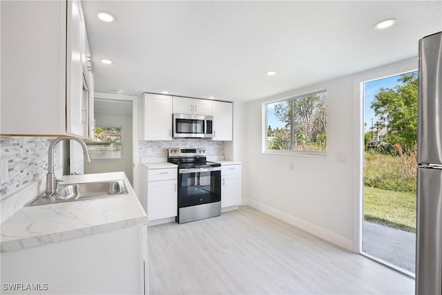 kitchen with white cabinetry, sink, tasteful backsplash, and stainless steel appliances