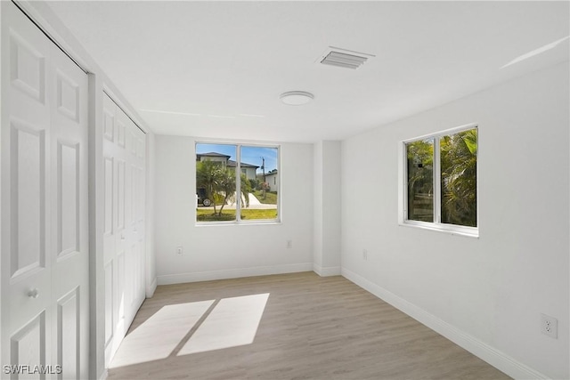 unfurnished bedroom featuring multiple windows and light hardwood / wood-style flooring