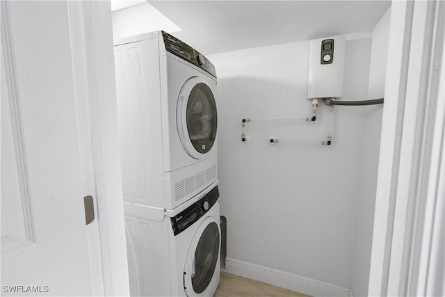 laundry area featuring tankless water heater, stacked washer / dryer, and light hardwood / wood-style flooring