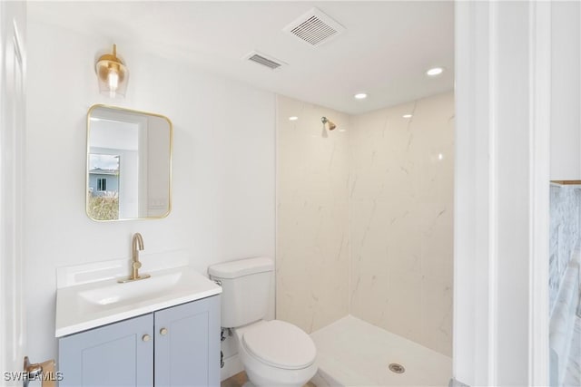 bathroom featuring vanity, toilet, and a tile shower