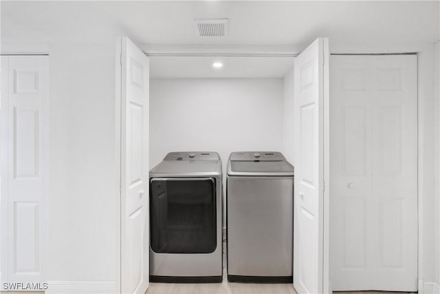 clothes washing area featuring washer and clothes dryer and light wood-type flooring