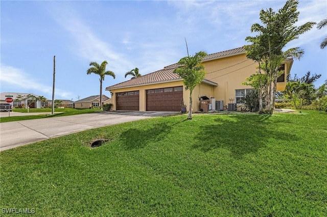 view of front of home with a garage, central AC, and a front lawn