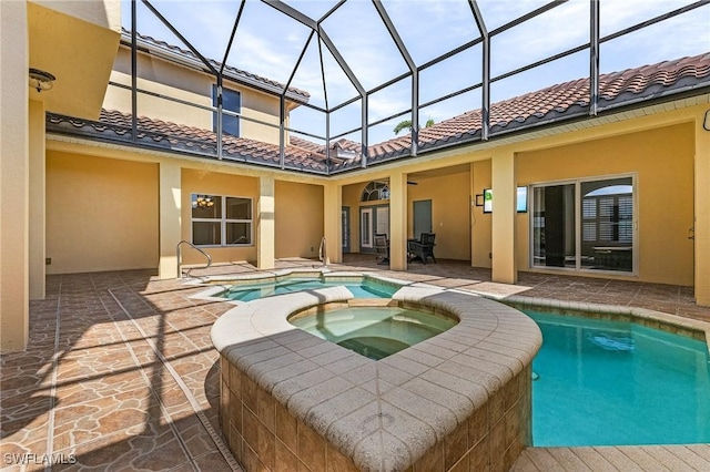 view of pool featuring an in ground hot tub, ceiling fan, a patio area, and glass enclosure