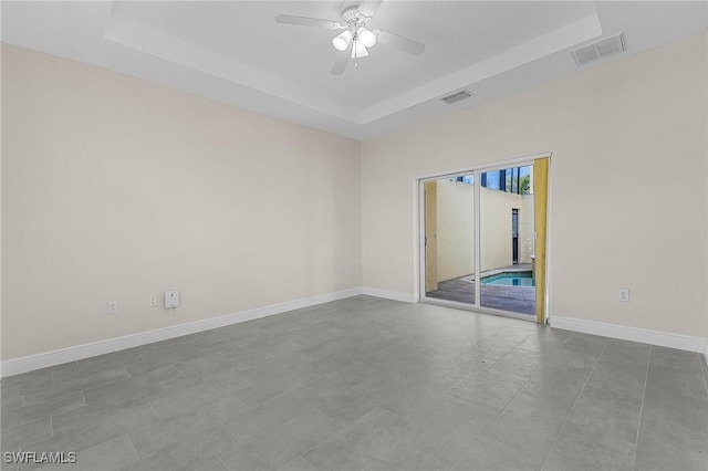 empty room featuring a tray ceiling and ceiling fan