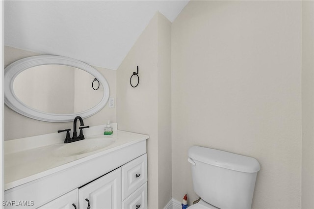 bathroom featuring vanity, toilet, and vaulted ceiling