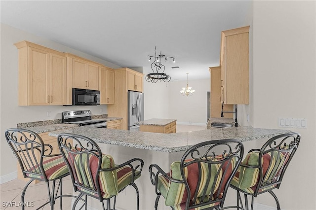 kitchen with sink, a breakfast bar area, appliances with stainless steel finishes, an inviting chandelier, and kitchen peninsula