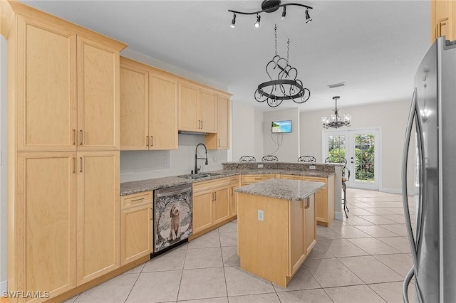 kitchen featuring light brown cabinetry, sink, light stone counters, a center island, and appliances with stainless steel finishes