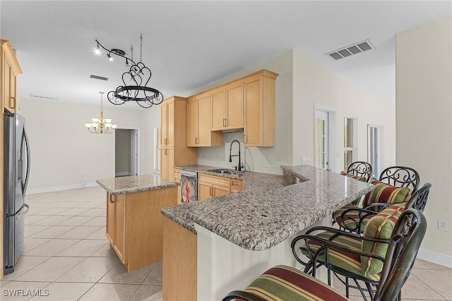 kitchen featuring sink, decorative light fixtures, a center island, appliances with stainless steel finishes, and a kitchen breakfast bar