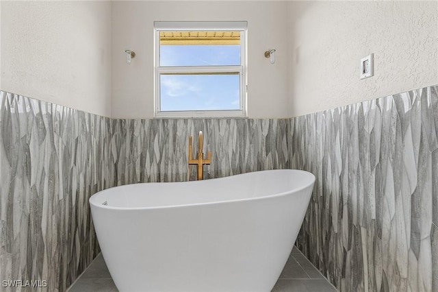 bathroom with tile walls, tile patterned floors, and a tub to relax in