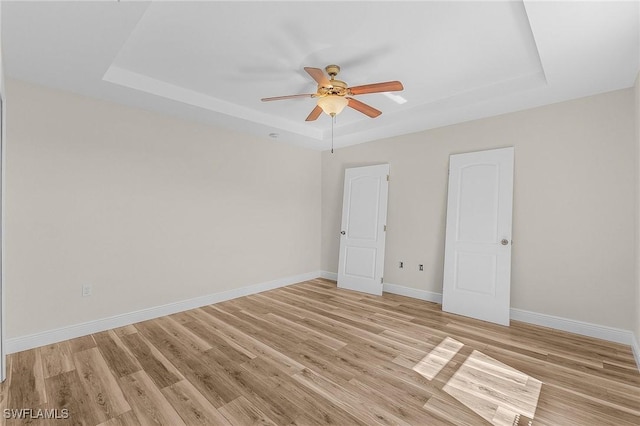 unfurnished bedroom with a raised ceiling, ceiling fan, and light hardwood / wood-style flooring