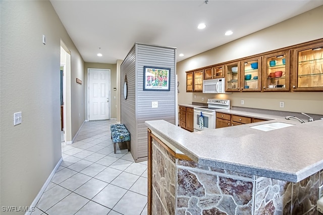 kitchen with sink, white appliances, kitchen peninsula, and light tile patterned floors