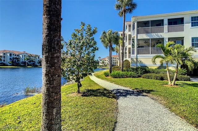 view of yard featuring a water view, ceiling fan, and a balcony