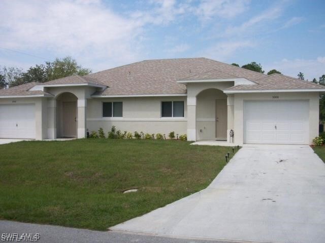single story home with stucco siding, an attached garage, driveway, and a front lawn