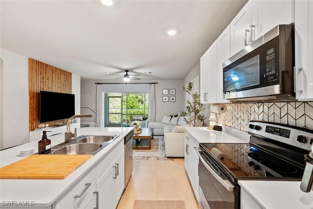 kitchen featuring sink, light tile patterned floors, stainless steel appliances, and white cabinets