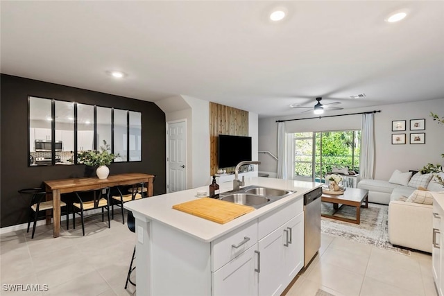 kitchen with light tile patterned flooring, sink, white cabinets, a kitchen island with sink, and stainless steel appliances