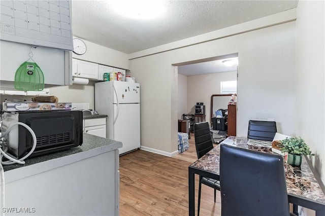 kitchen featuring a textured ceiling, light hardwood / wood-style flooring, white cabinets, and white refrigerator