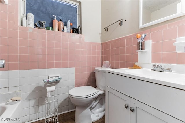 bathroom with vanity, a washtub, toilet, and tile walls