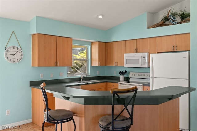 kitchen featuring a breakfast bar, sink, light tile patterned floors, kitchen peninsula, and white appliances