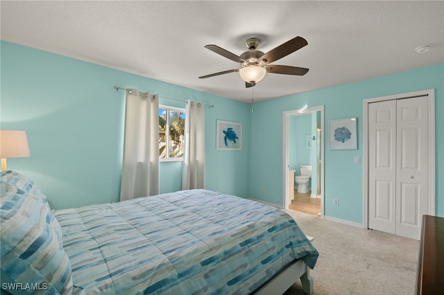 bedroom featuring ensuite bath, light colored carpet, ceiling fan, a textured ceiling, and a closet