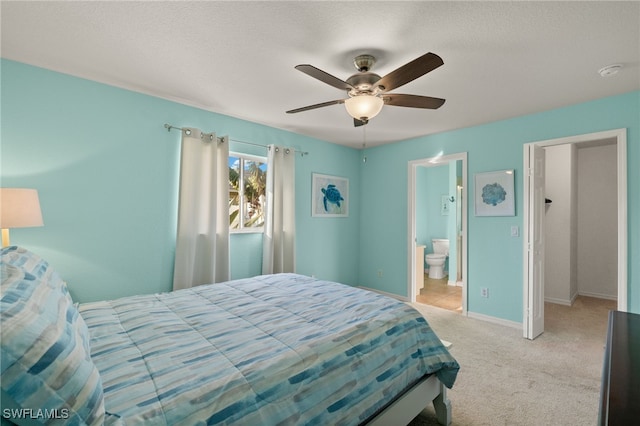 bedroom featuring light carpet, a textured ceiling, ceiling fan, and ensuite bath