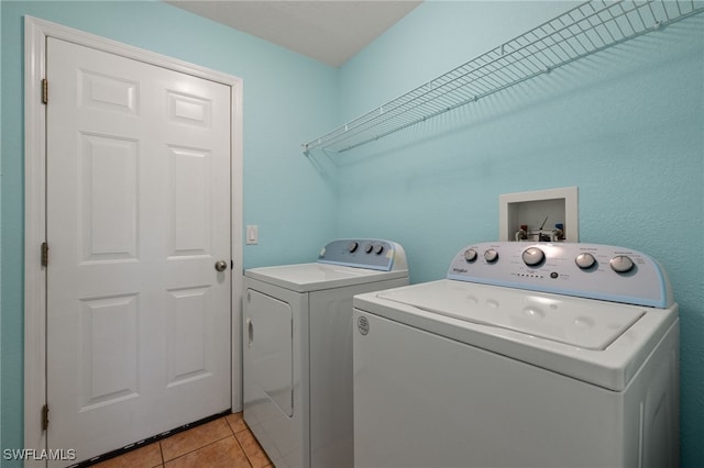 clothes washing area featuring light tile patterned floors and washing machine and clothes dryer