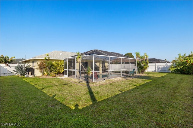 rear view of property with a yard, a patio, and glass enclosure