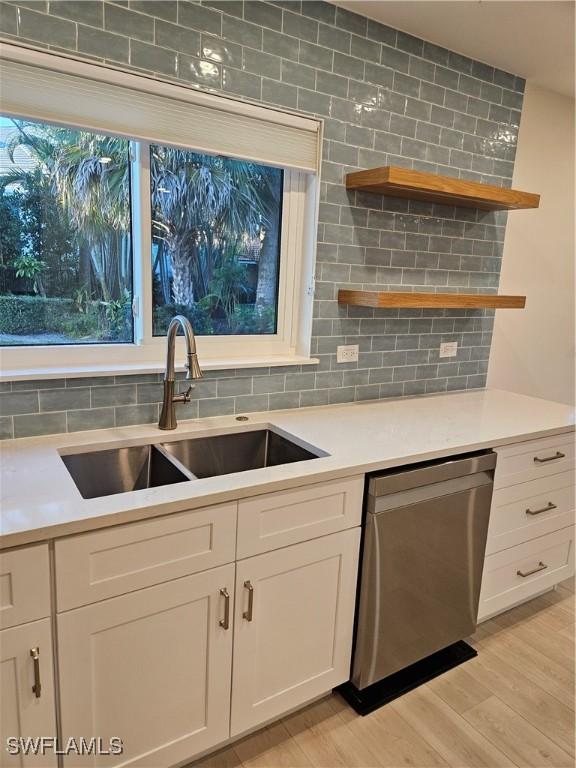 kitchen with white cabinetry, dishwasher, sink, and decorative backsplash