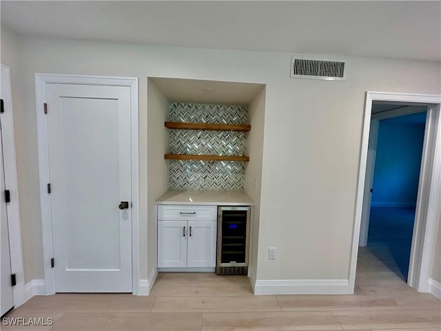 bar featuring white cabinets, tasteful backsplash, and beverage cooler