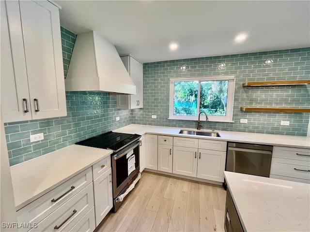 kitchen with sink, custom exhaust hood, white cabinetry, appliances with stainless steel finishes, and backsplash