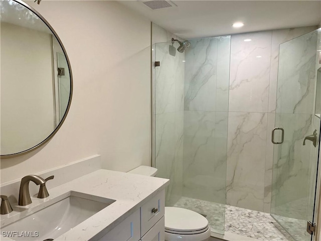 bathroom with vanity, a shower with door, and toilet