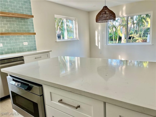 kitchen with white cabinetry, hanging light fixtures, and tasteful backsplash