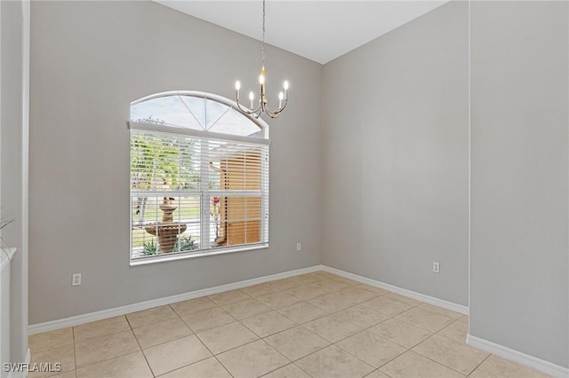 tiled spare room with vaulted ceiling and a notable chandelier